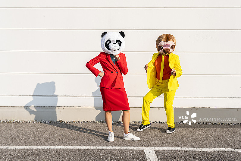 男人和女人戴着动物面具站在墙前图片素材