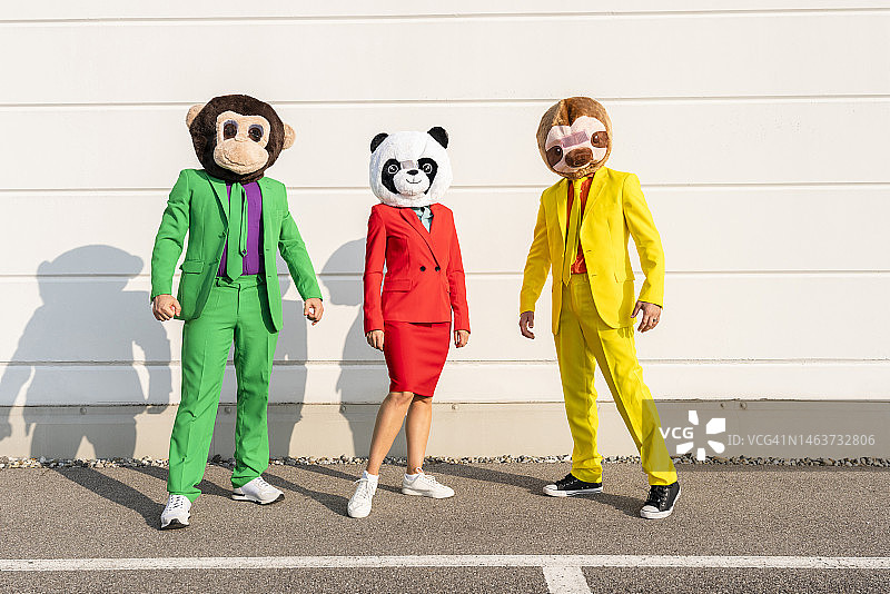 戴着动物面具站在墙前的男女图片素材