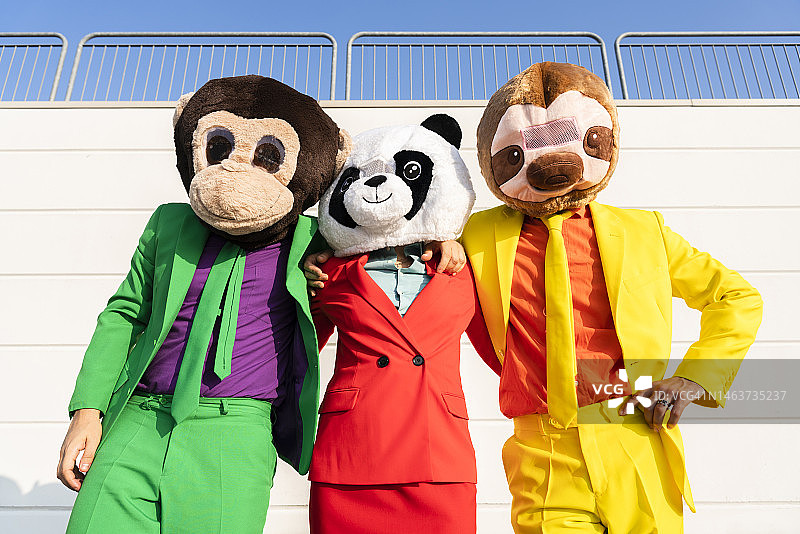 戴着动物面具的女人和朋友们站在墙前图片素材