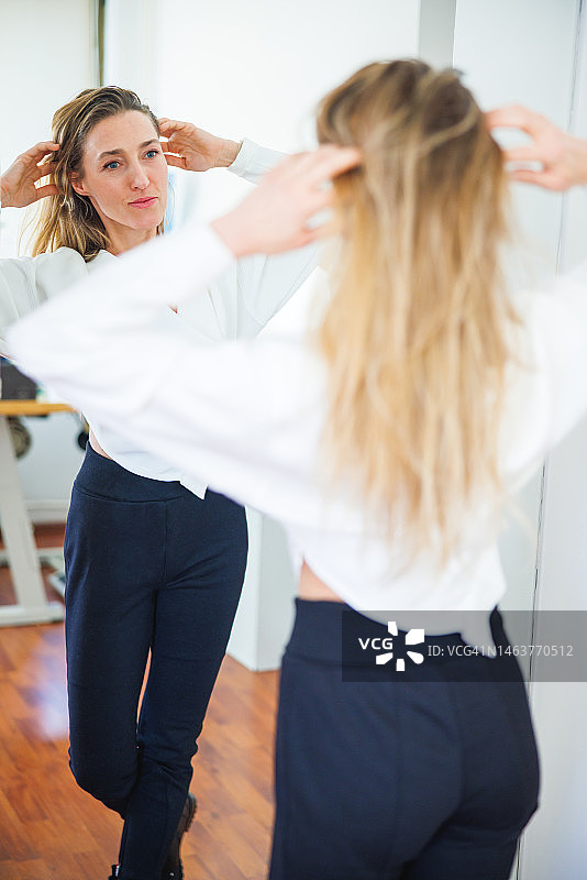 对着镜子试穿白色衬衫和黑色裤子的中年妇女图片素材
