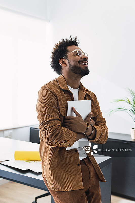 办公室商务人士手持笔记本电脑靠在桌旁图片素材