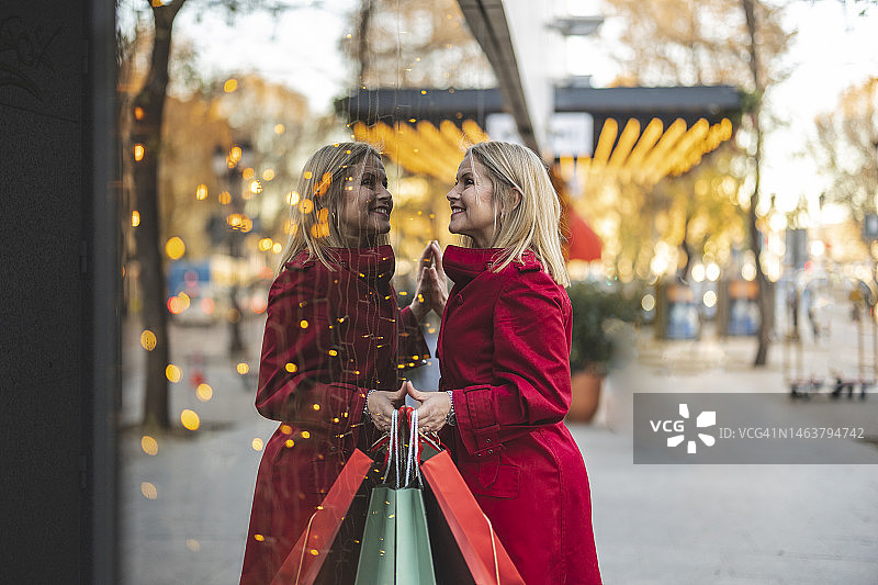 面带微笑的中年妇女倚靠在商店橱窗上图片素材