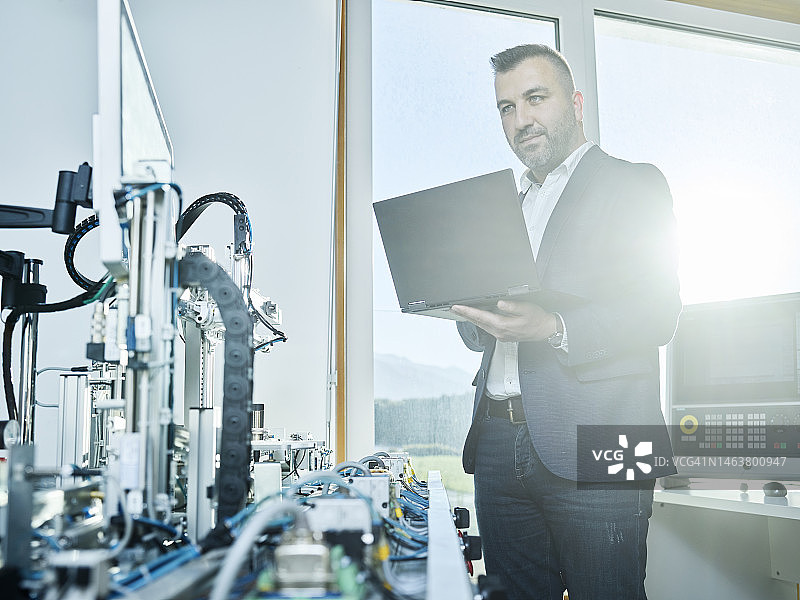 在现代工厂中使用笔记本电脑的商人图片素材