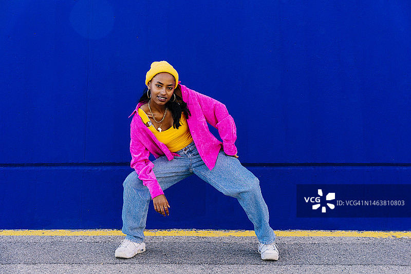 在人行道上跳舞的穿着夹克的微笑年轻女人图片素材