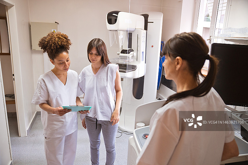女医生向检查室的病人解释乳腺X光检查报告图片素材