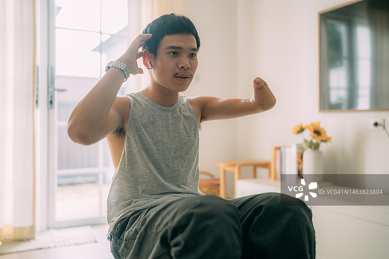 在家用瑜伽垫做仰卧起坐的安装假肢的年轻男人图片素材