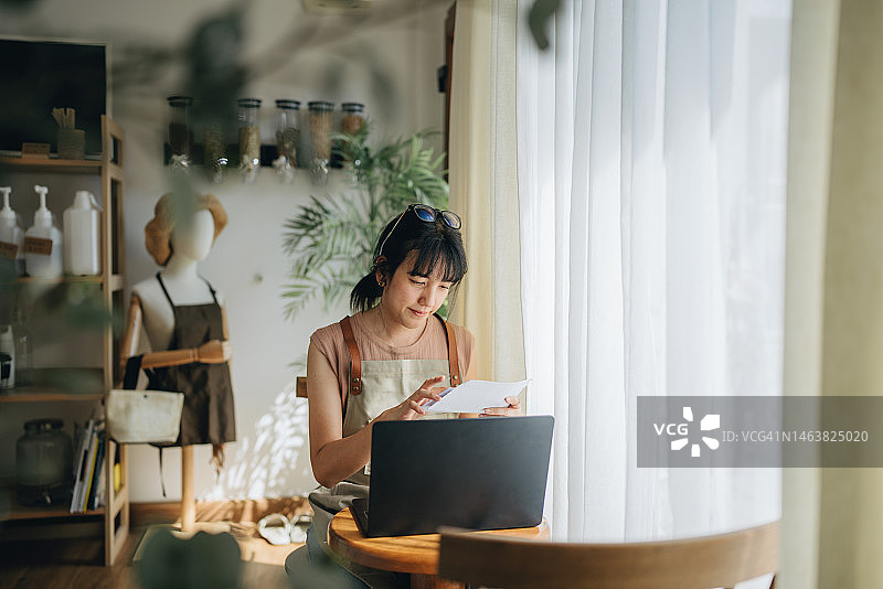 年轻女店主在她的商店里计算开支图片素材