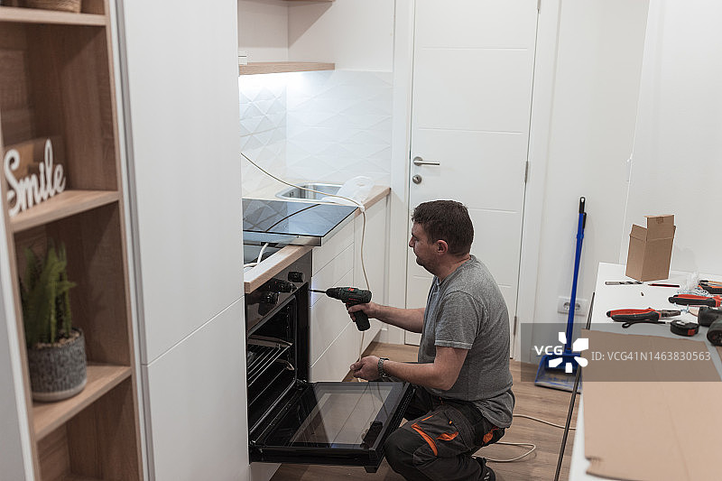 修理工在厨房安装新炉子图片素材
