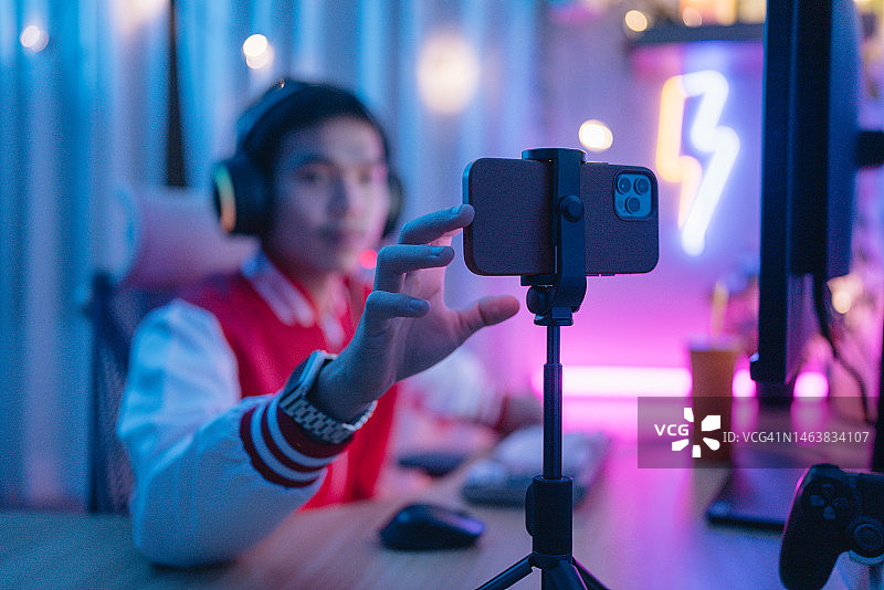 亚洲残疾男子在房间里用智能手机玩激动人心的游戏图片素材