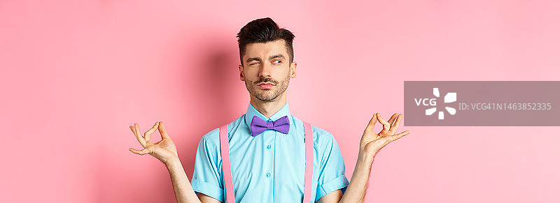 戴着小胡子和蝴蝶结的有趣男人假装冥想，向一旁偷看图片素材