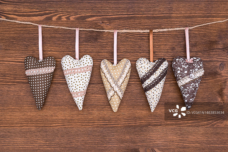 悬挂在棕色木绳上的棕色、米色和白色织物心形图片素材