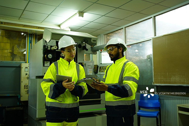 两名工程师在工厂维修机器，检查生产零件的质量图片素材