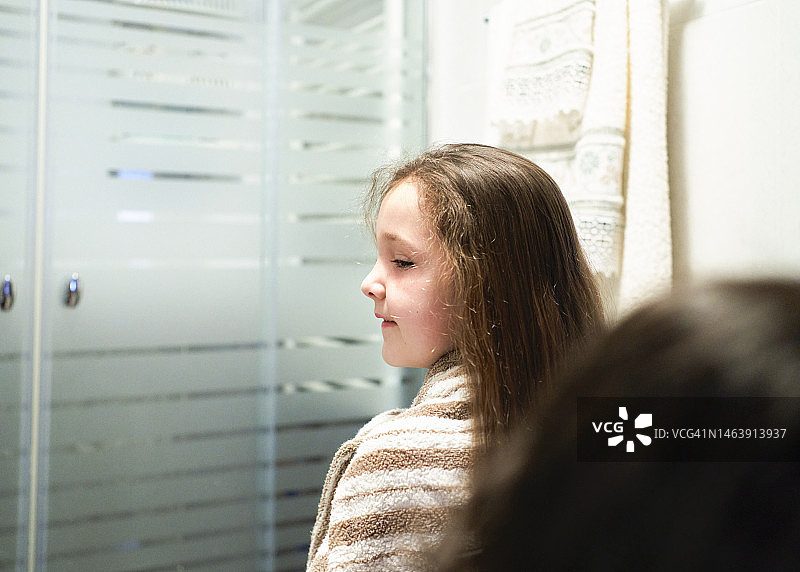 身穿红色休闲装的女人和裹着条纹毛巾的孩子在室内浴室图片素材