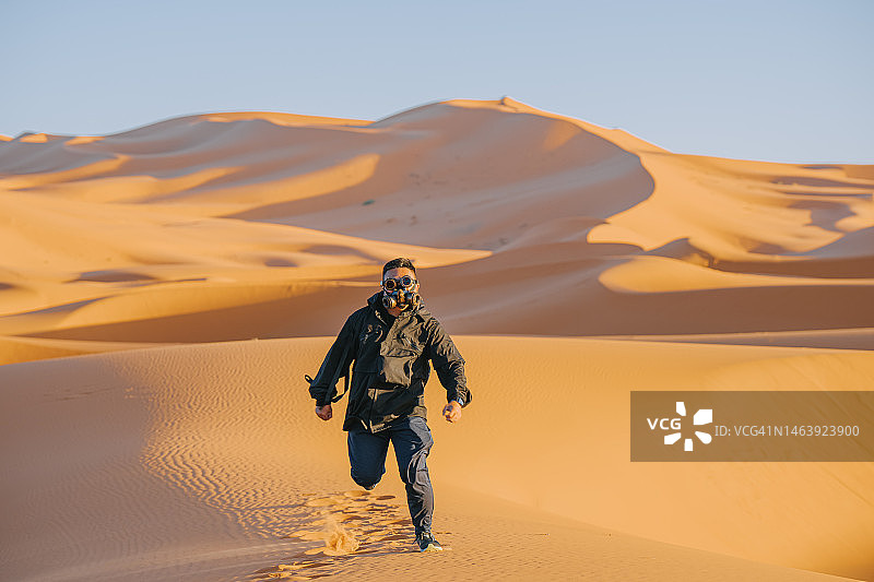 戴着蒸汽朋克面具的中国男子在撒哈拉沙漠图片素材