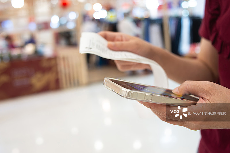 女人使用智能手机扫描账单上的二维码进行在线支付图片素材