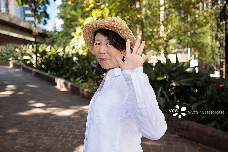 在户外挥手的微笑的女人图片素材