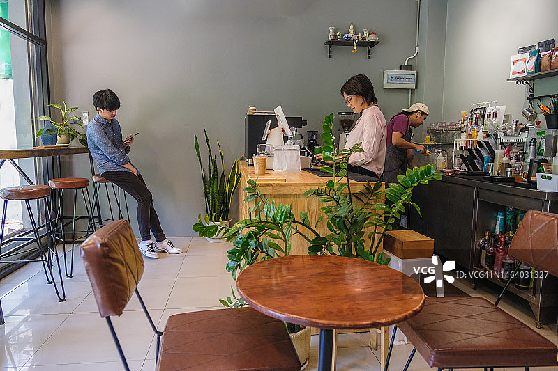 年轻亚洲咖啡师或咖啡店主在咖啡馆的吧台制作咖啡图片素材