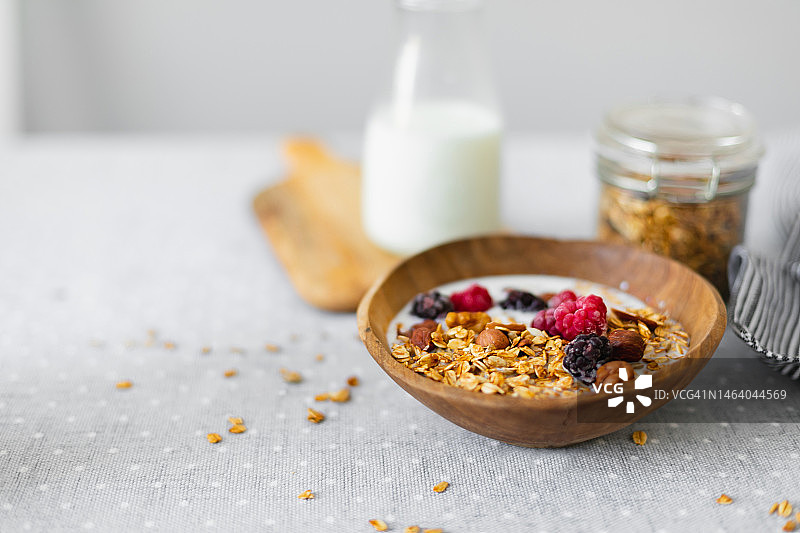 小木碗里的牛奶、烤格兰诺拉麦片和浆果图片素材