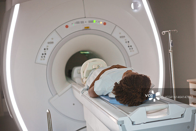 年轻女患者躺在医疗检查室的核磁共振扫描仪上图片素材
