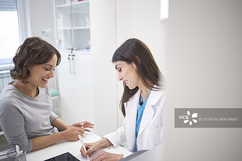 医生与女性患者在诊所、医院讨论医疗保健问题图片素材