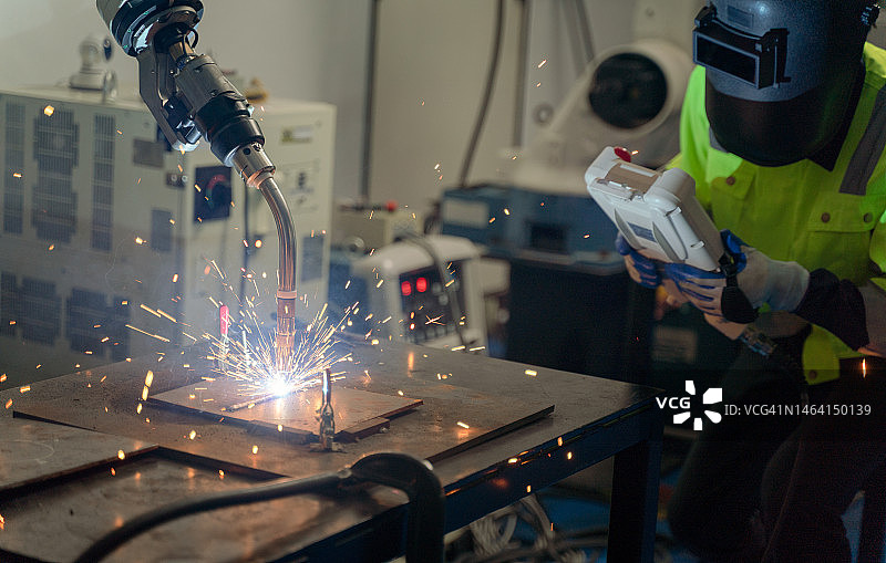 工程师控制机器人焊接正在工厂焊接组装汽车零件图片素材