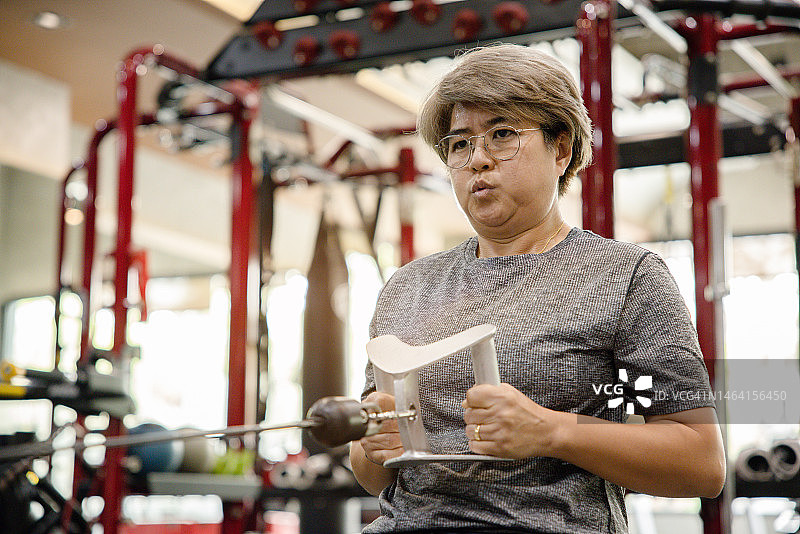 中年妇女在健身房使用引体向上器械锻炼图片素材