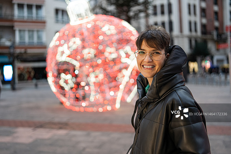 夜晚在有圣诞装饰的街道上行走的女人图片素材