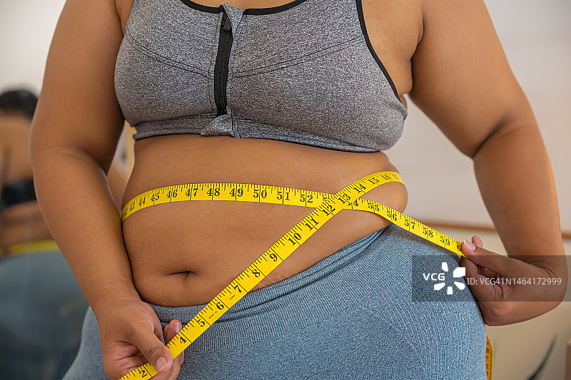 加大码女性用卷尺测量腰围图片素材