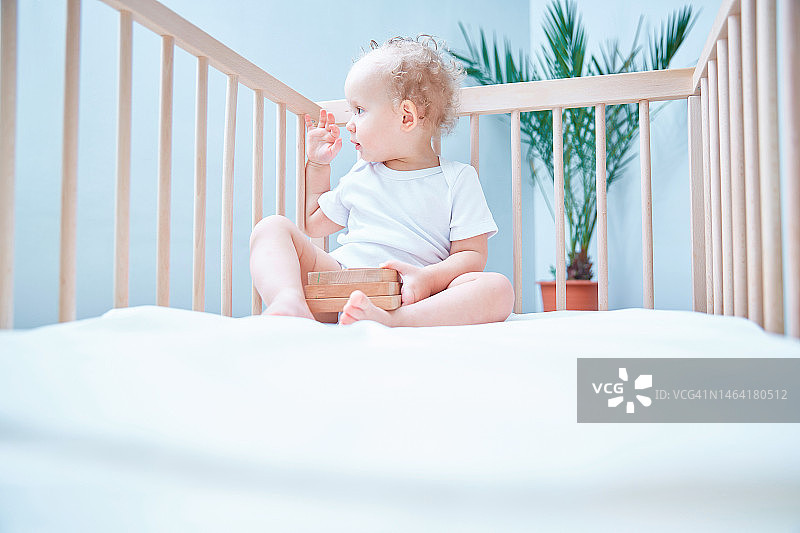 卷发小女孩坐在床上四处张望，留白，俄罗斯图片素材