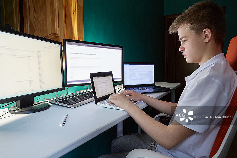 俄罗斯少年坐在大量显示器后图片素材