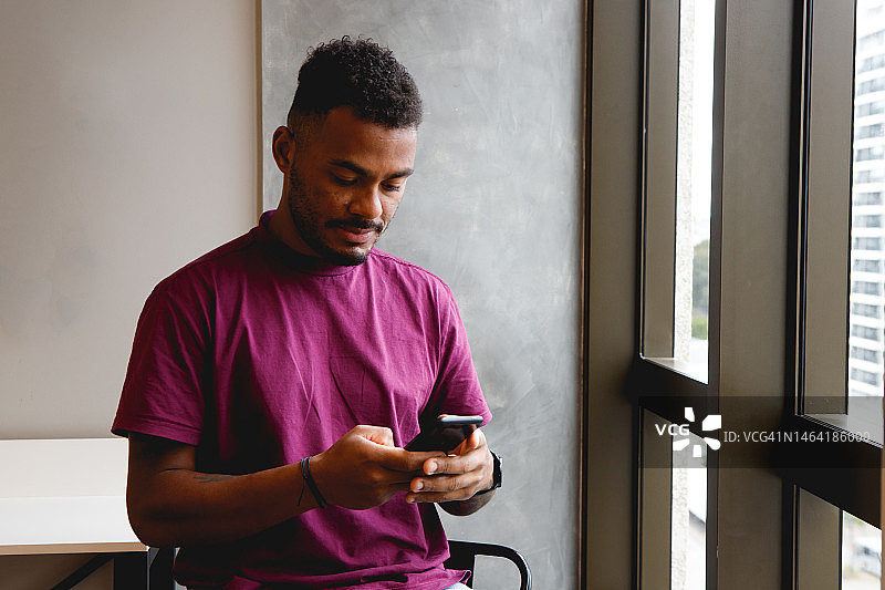 男人在窗边看智能手机图片素材