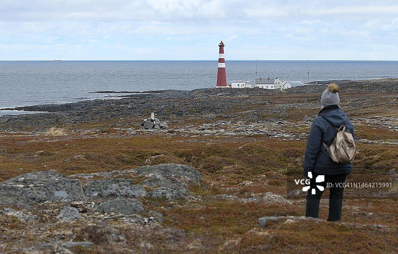 在苔原上看巴伦支海Gamvik灯塔的女子，挪威北部，斯堪的纳维亚图片素材
