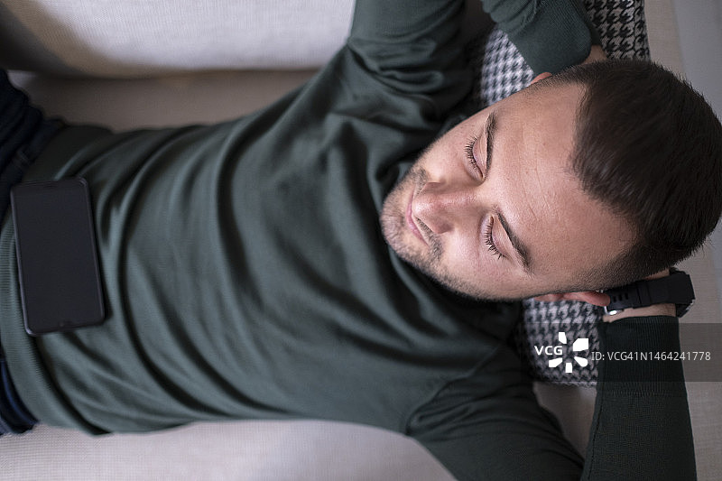 疲惫的男人下班回家后瘫倒在沙发上图片素材