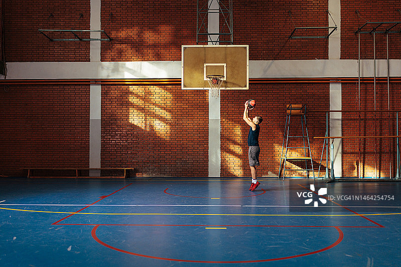 男人在空旷的球场上练习篮球图片素材
