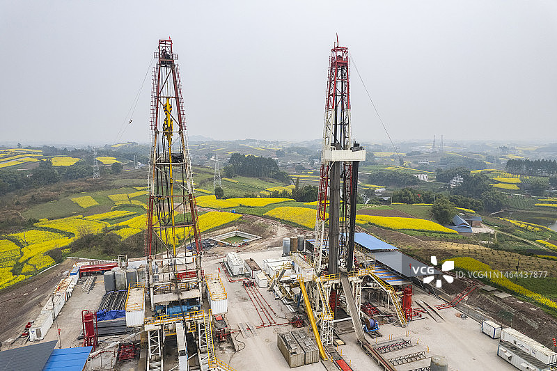 四川南部油菜花田中页岩气钻井现场航拍照片图片素材