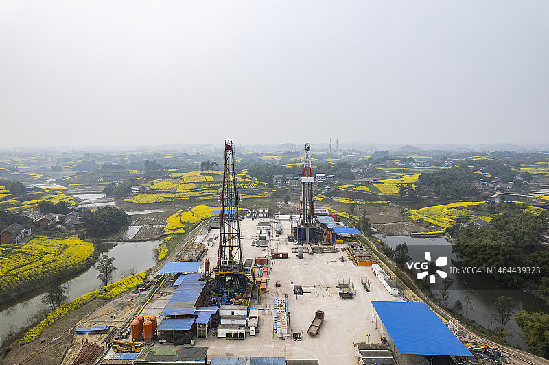 四川南部油菜花田中页岩气钻井现场航拍照片图片素材