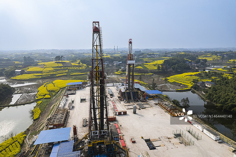 四川南部油菜花田中页岩气钻井现场航拍照片图片素材