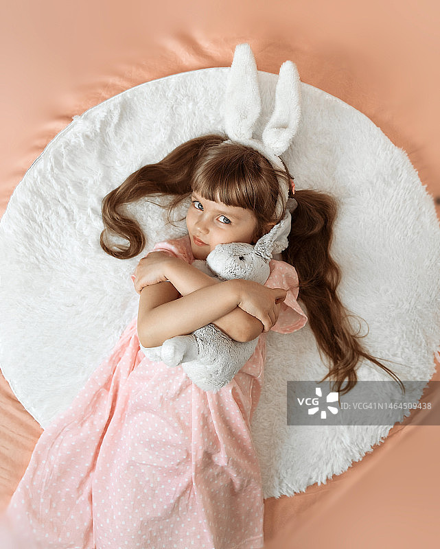 一个棕色头发的可爱微笑的小女孩躺在床上图片素材