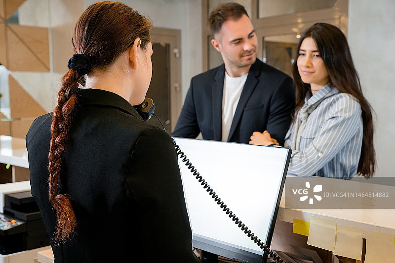 在酒店前台办理入住的年轻情侣图片素材