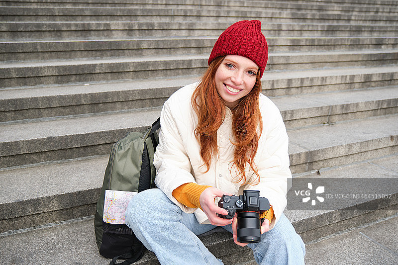 年轻女摄影师的肖像，手持专业相机坐在楼梯上图片素材