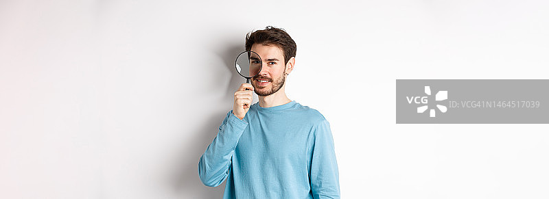 面带微笑用放大镜观察的年轻男侦探图片素材