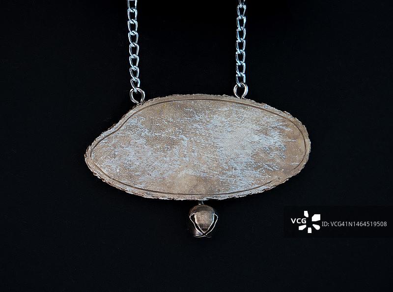 黑色背景上悬挂在金属链上的木制标牌特写图片素材