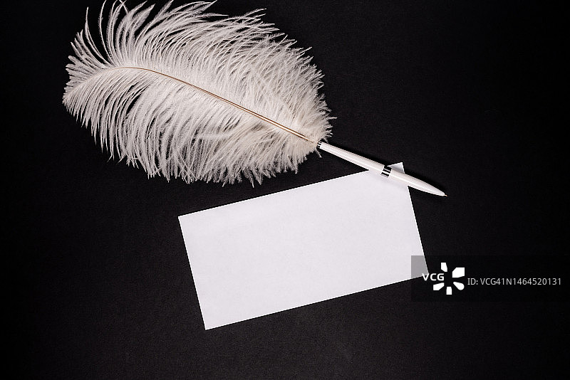 黑色背景上的带复古羽毛笔的白色空信封图片素材