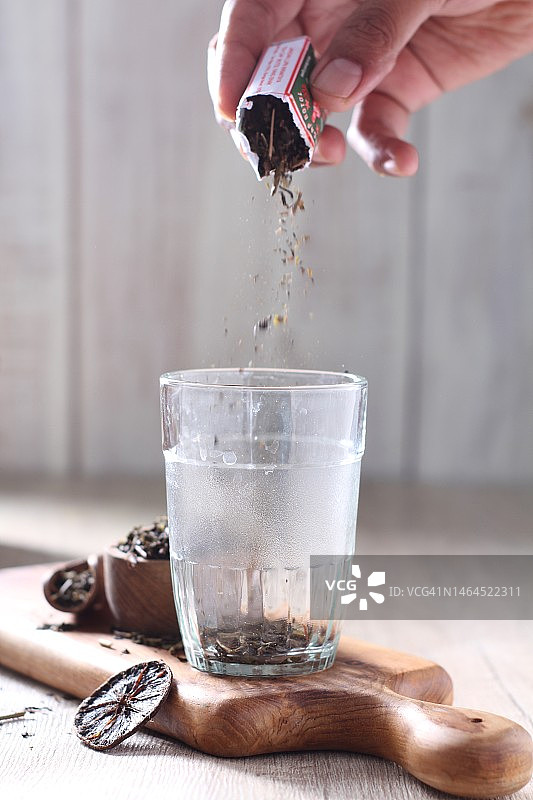 往桌子上的玻璃杯里倒水的局部特写图片素材
