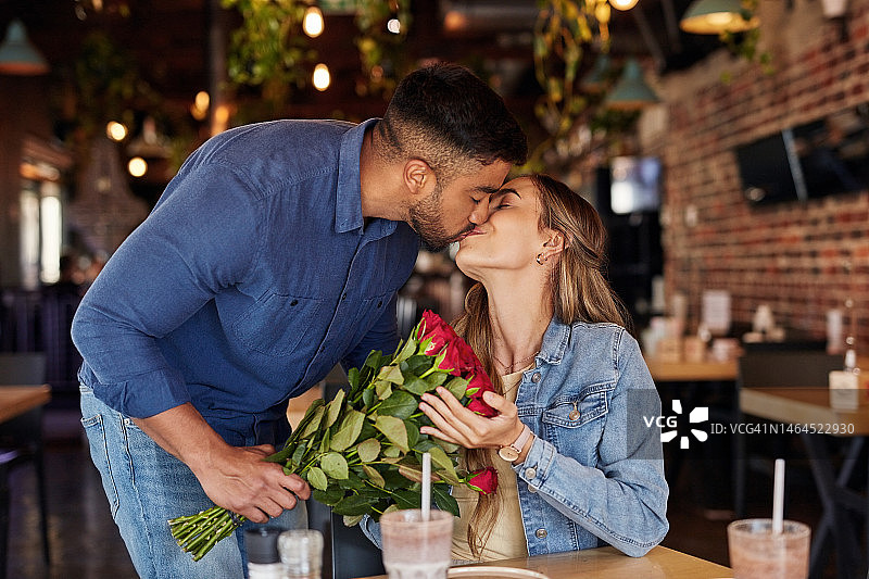 爱，情侣在咖啡馆亲吻，玫瑰和庆祝关系，周年纪念日和浪漫。情人节，男人或女人在咖啡店，鲜花或爱意，约会，幸福或浪漫图片素材