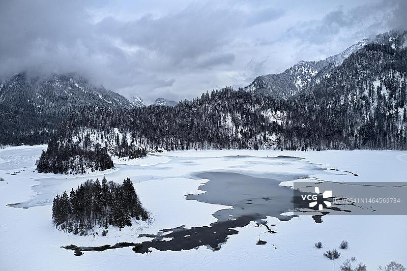 冬季山区冰雪覆盖的湖面，多云，白雪覆盖的树木，德国巴伐利亚州基姆高的德莱森地区图片素材