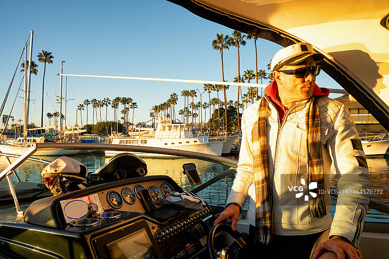 游艇船长在热带码头，背景是棕榈树和帆船图片素材