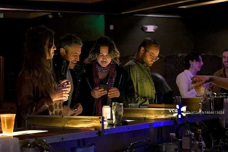 在酒吧里朋友们聊天看手机图片素材