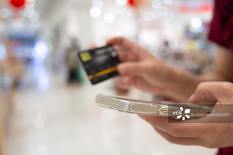 在线支付：人手持信用卡并使用智能手机进行网上购物图片素材