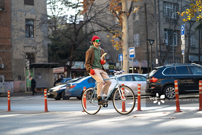 骑自行车手持格鲁吉亚面包的现代千禧一代图片素材